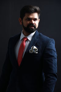 Thoughtful businessman wearing suit while standing against black background