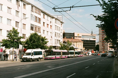 Cars on city street by buildings against sky