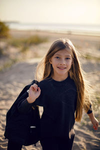 Portrait of a girl with long hair run on a sandy beach in a black leather jacket