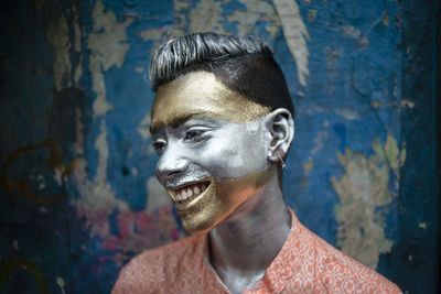 Close-up portrait of smiling young man against wall