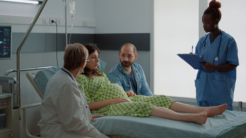 Doctor and nurse talking with pregnant woman in hospital