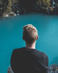 Rear view of man sitting over lake