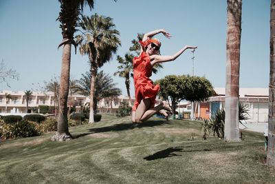 Woman jumping in park against clear sky