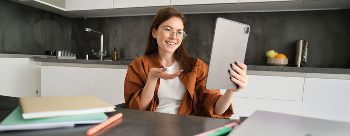 Portrait of young woman using mobile phone on table