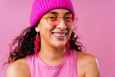 Portrait of young woman against pink background