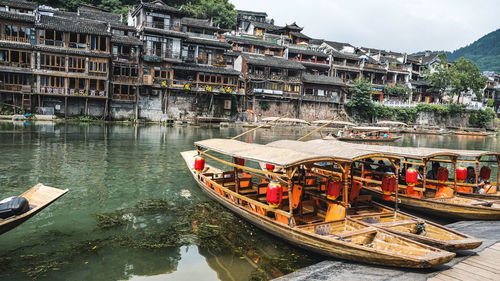 Boats moored in river by buildings
