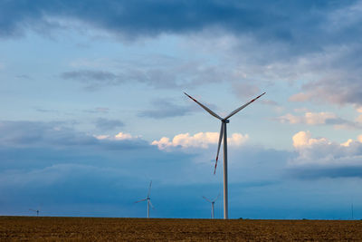 Wind turbines on field against sky