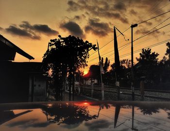 Silhouette trees by swimming pool against sky during sunset