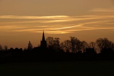 Silhouette trees and building against sky during sunset