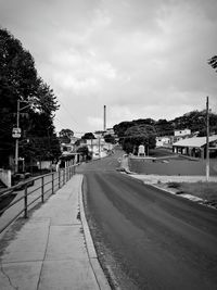Road by buildings in city against sky