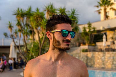 Shirtless young man wearing sunglasses at resort
