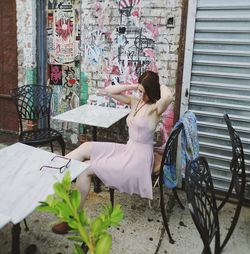 Woman sitting on chair by wall