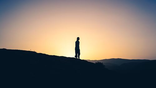 Silhouette man standing on mountain against clear sky