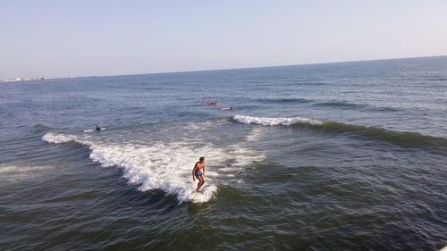 Man surfing on sea against clear sky