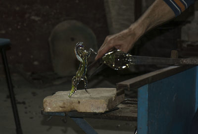 Cropped hand of man making glass sculpture at workshop