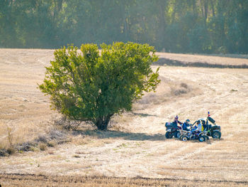 People with quadbikes on field during sunny day