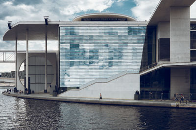 Buildings by river against sky in city