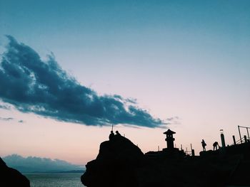 Silhouette rocks by sea against sky during sunset