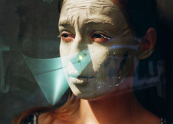 Reflection of woman with facial mask against jewelry in window