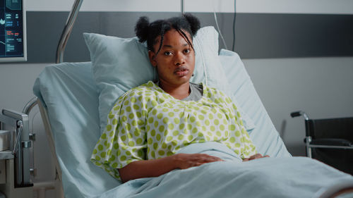 Portrait of female patient sitting on bed at hospital
