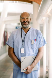 Portrait of smiling male nurse standing in hospital corridor