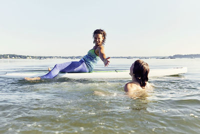 Two young female friends on standup paddle board in casco bay, maine