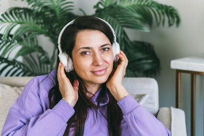 A woman in headphones listens to her favorite music at home on the couch.
