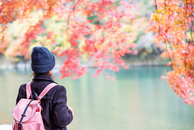 Rear view of person standing by lake