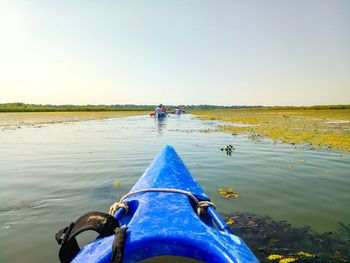 People on lake against clear sky