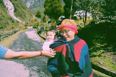 Cropped image of hand touching baby carried by mother