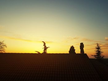 Silhouette roof of building against sky during sunset