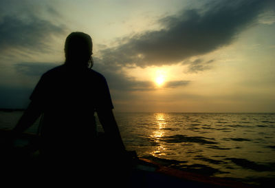 Silhouette of people in sea at sunset