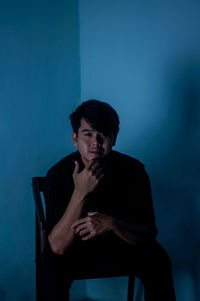 Portrait of young man standing against blue wall