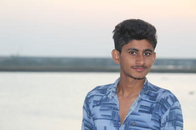 Portrait of young man standing against sky during sunset