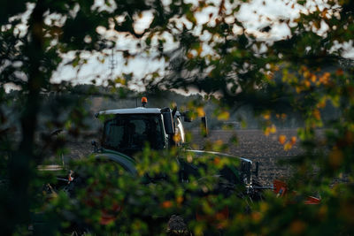 Tractor on field against trees