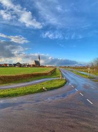 Road amidst field against sky in city