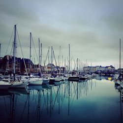 Boats moored at harbor in sea against sky