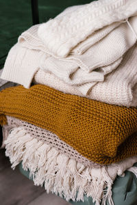 Stack of women's dresses with knitted wool sweaters or plaids. various knitting patterns, stacked