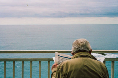 Rear view of man looking at sea against sky