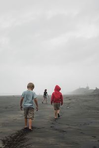 Rear view of people walking on road against sky