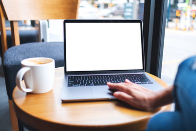 Mockup image of a hand touching on laptop computer touchpad with blank white desktop screen