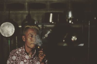 Mature man smoking while standing in kitchen