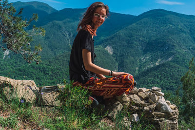 Woman sitting on wicker basket against mountains