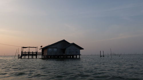 House by sea against sky during sunset