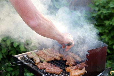 Man preparing food on barbecue grill in yard