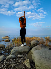 Girl in a yellow sweater on a stone near the sea