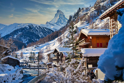 Snow covered buildings and mountains against sky