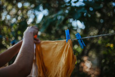 Cropped hand of woman drying clothes on clothesline