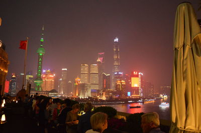 Illuminated modern buildings in city against sky at night