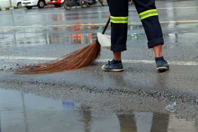 Low section of man with umbrella on wet street